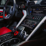 A white Lamborghini Urus with a luxurious black and red interior and a starry headliner, parked in a modern showroom.