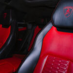A white Lamborghini Urus with a luxurious black and red interior and a starry headliner, parked in a modern showroom.