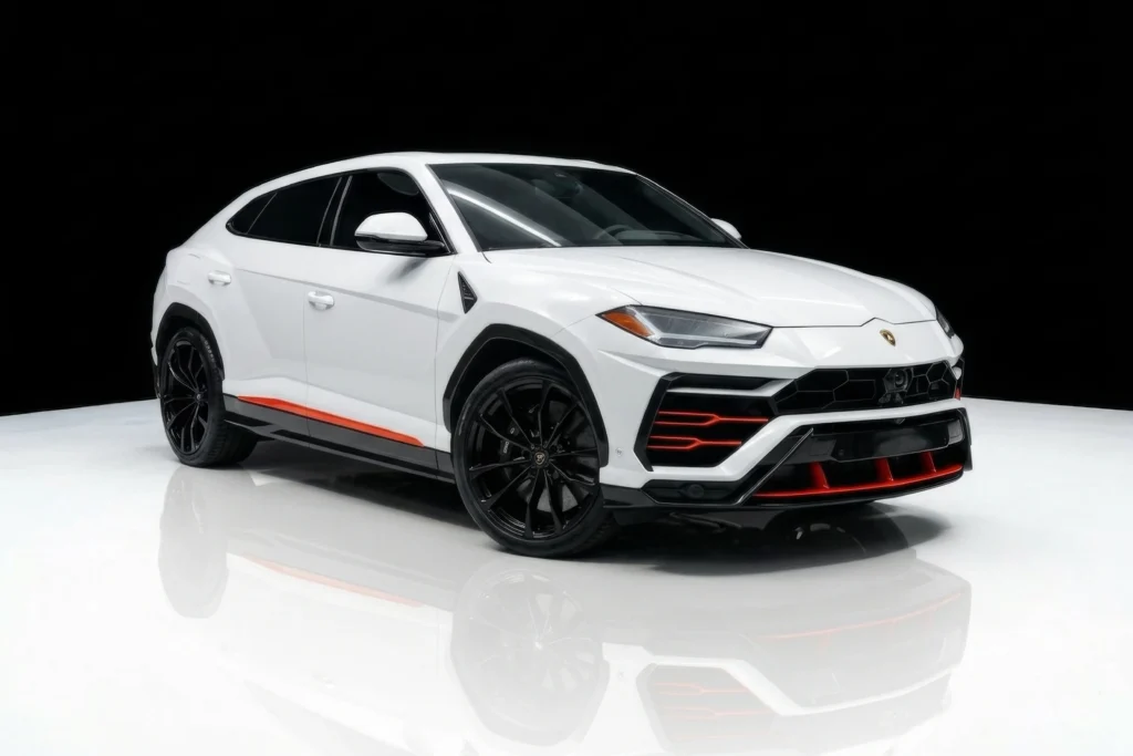Front angle view of a pristine white Lamborghini Urus with gloss black wheels and aggressive red lower accents parked in a studio.