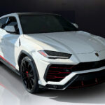 A white Lamborghini Urus with a luxurious black and red interior and a starry headliner, parked in a modern showroom.