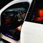 A white Bentley Bentayga with red interior seats, parked indoors, showcasing its luxurious and stylish design.