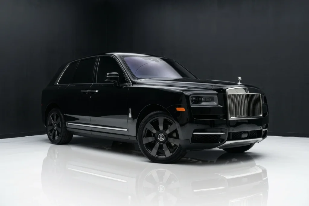 Front three quarter view of a sleek black Rolls-Royce Cullinan highlighting the massive chrome grille and dark alloy wheels.