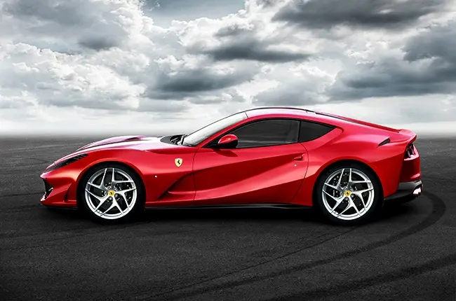Side profile of a red Ferrari 812 Superfast parked on an open road under dramatic clouds, showcasing its sleek design and V12 grand touring performance.